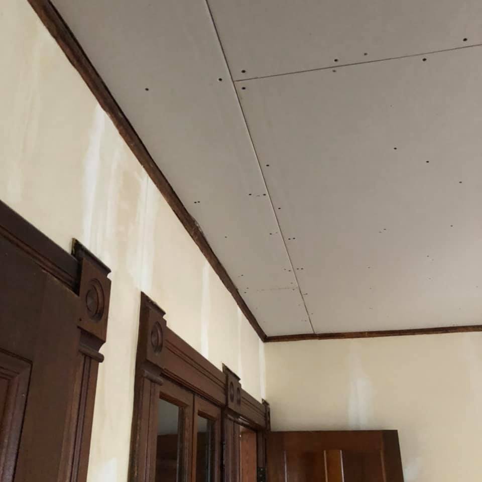 new drywall hung on ceiling of home with wood trim