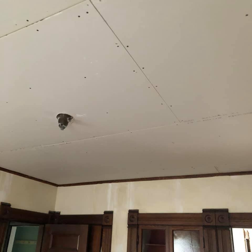 new drywall hung on ceiling of home with wood trim